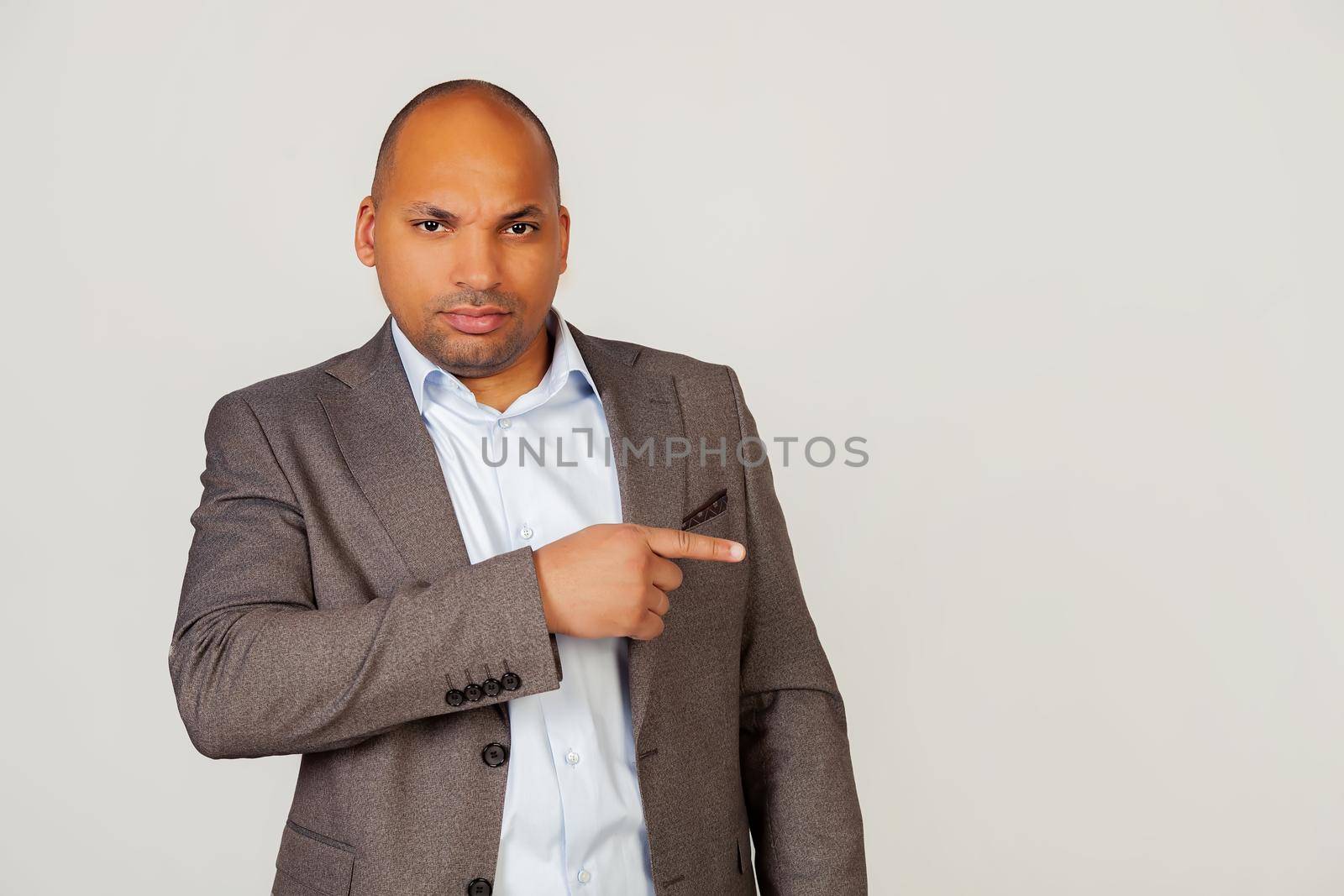 Young male African American businessman with a flirtatious expression, pointing his finger and frowning, squinting in confusion, seriously thinking about a difficult problem.