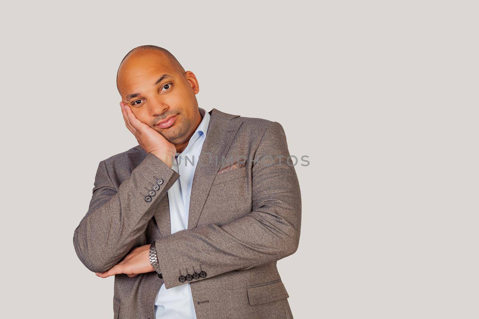 Handsome African-American young guy holding his head with his hand, being tired after a long and hard day at work.