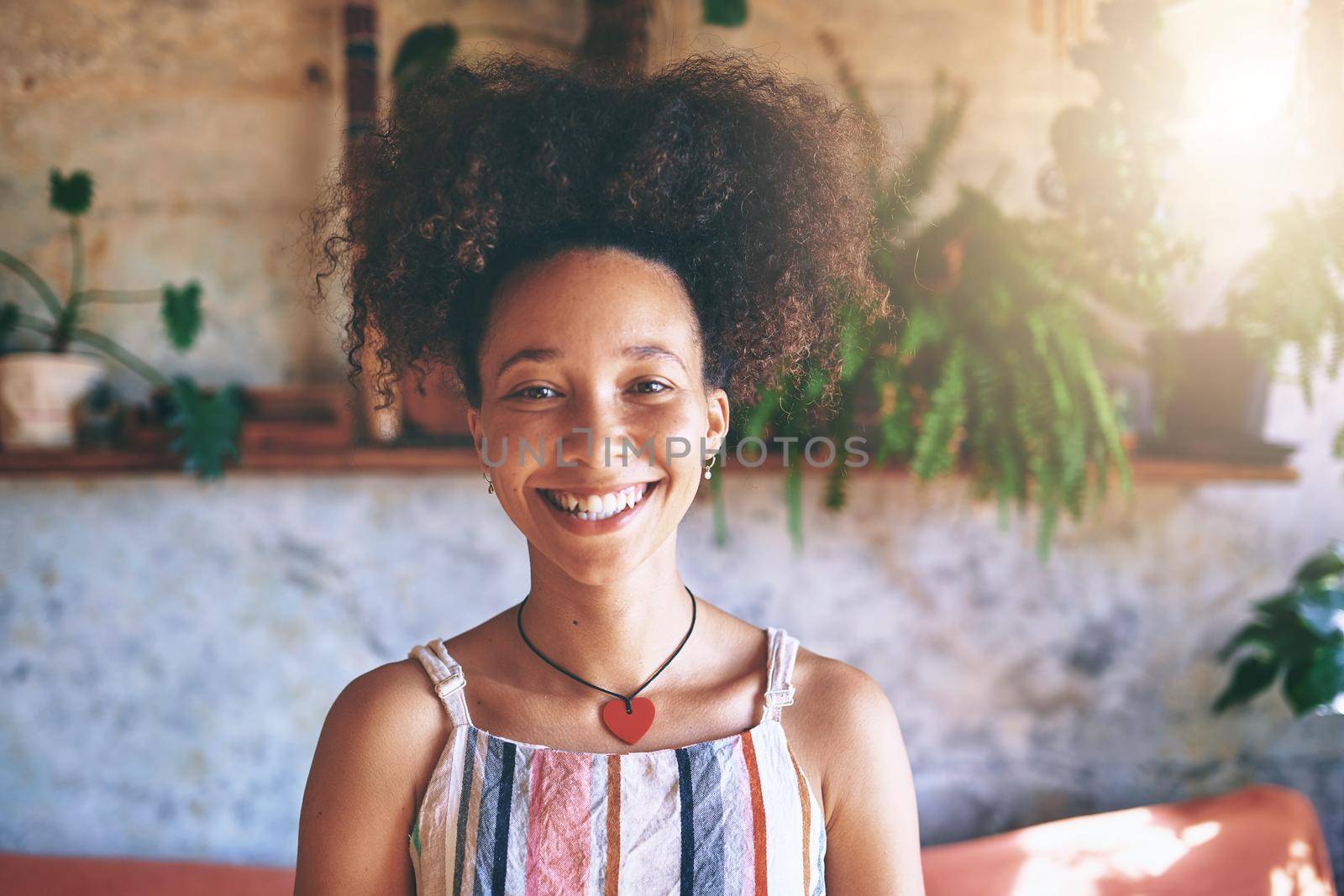 Portrait of a beautiful African woman smiling at the camera while at home in her living room - Stock Photo