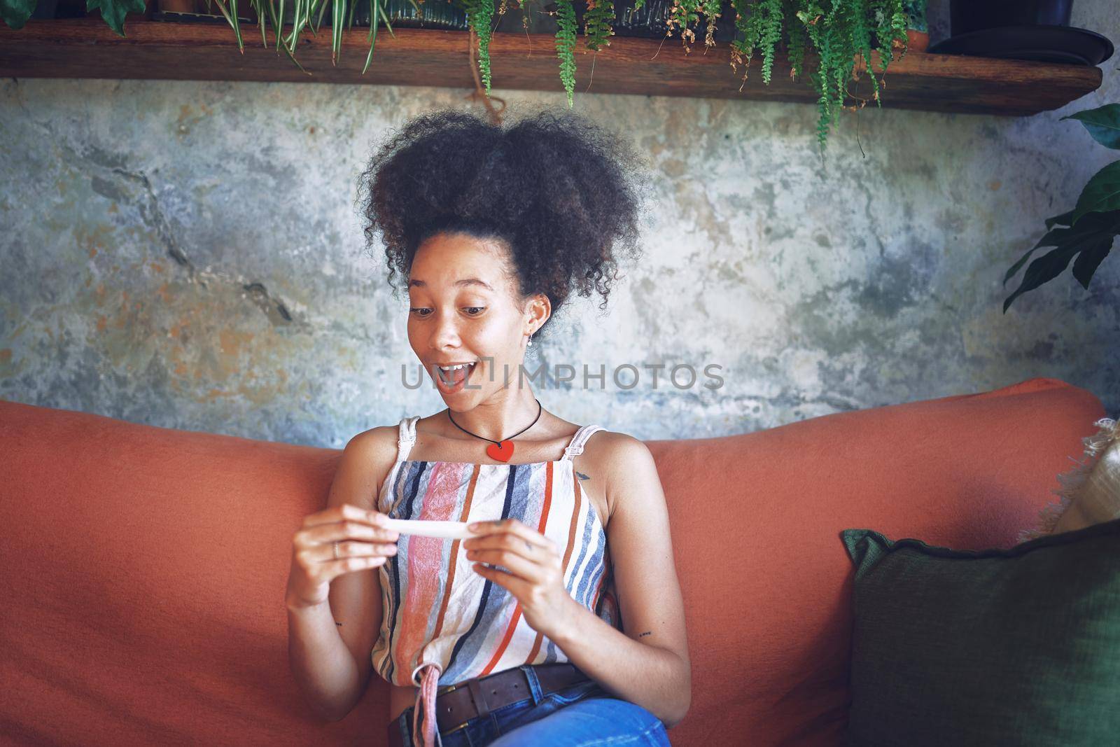 Shot of a young woman taking a pregnancy test on the sofa at home stock photo