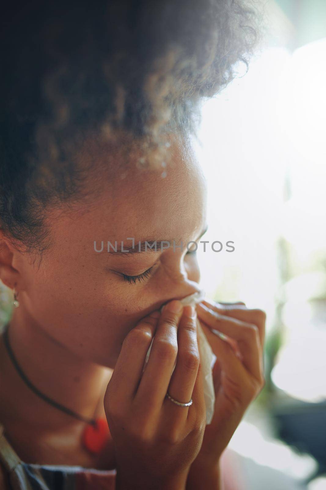 Close up shot of a young African woman blowing her nose