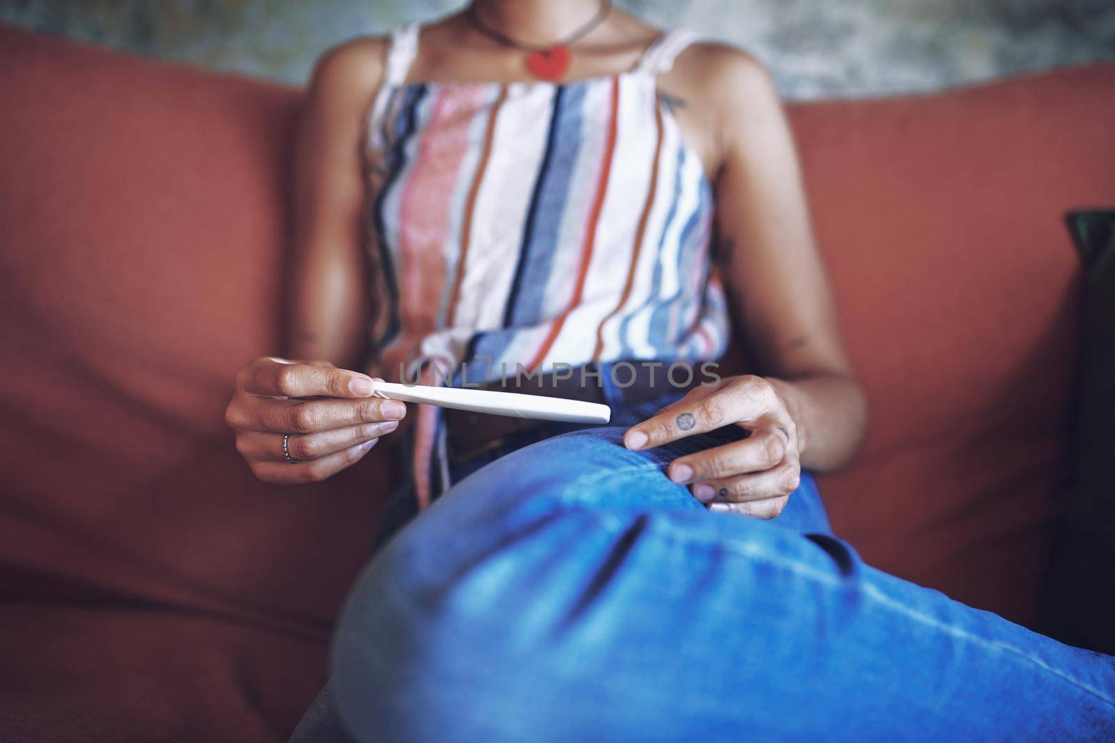 Cropped Shot of a young woman taking a pregnancy test on the sofa at home stock photo