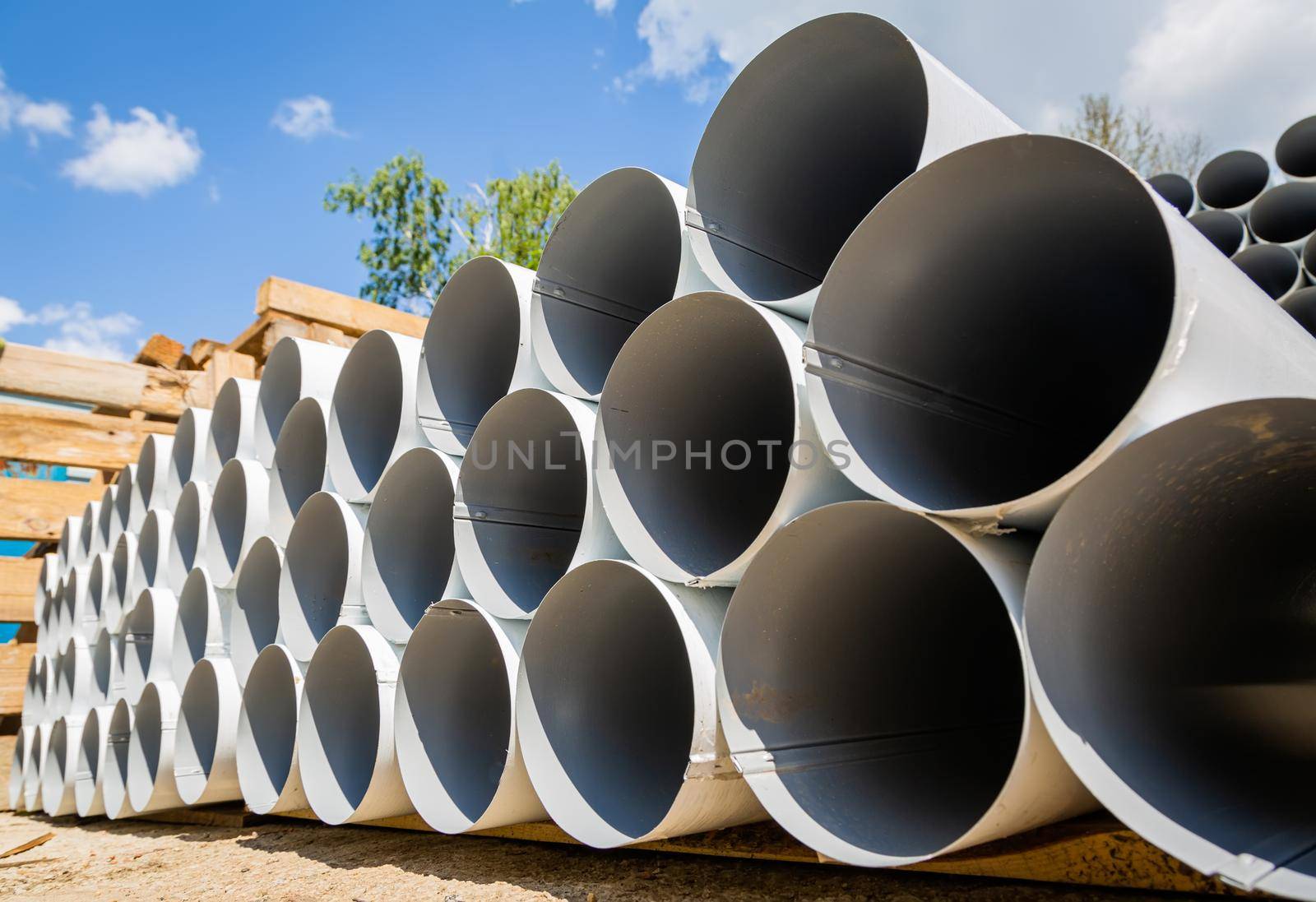 Downpipe warehouse. Steel pipes, parts for the construction of a roof drainage system in a warehouse. Stack of stainless steel pipes