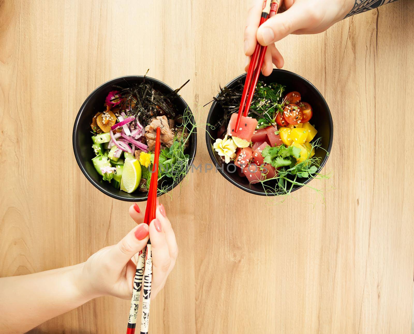 Man and woman eating poke salad with chopsticks. Dab tuna salad in a bowl. People in the restaurant eat salad with chopsticks. Asian seafood salad concept