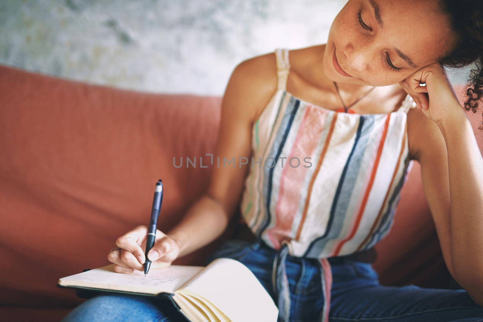 Shot of a young woman making notes while relaxing on the sofa at home stock photo