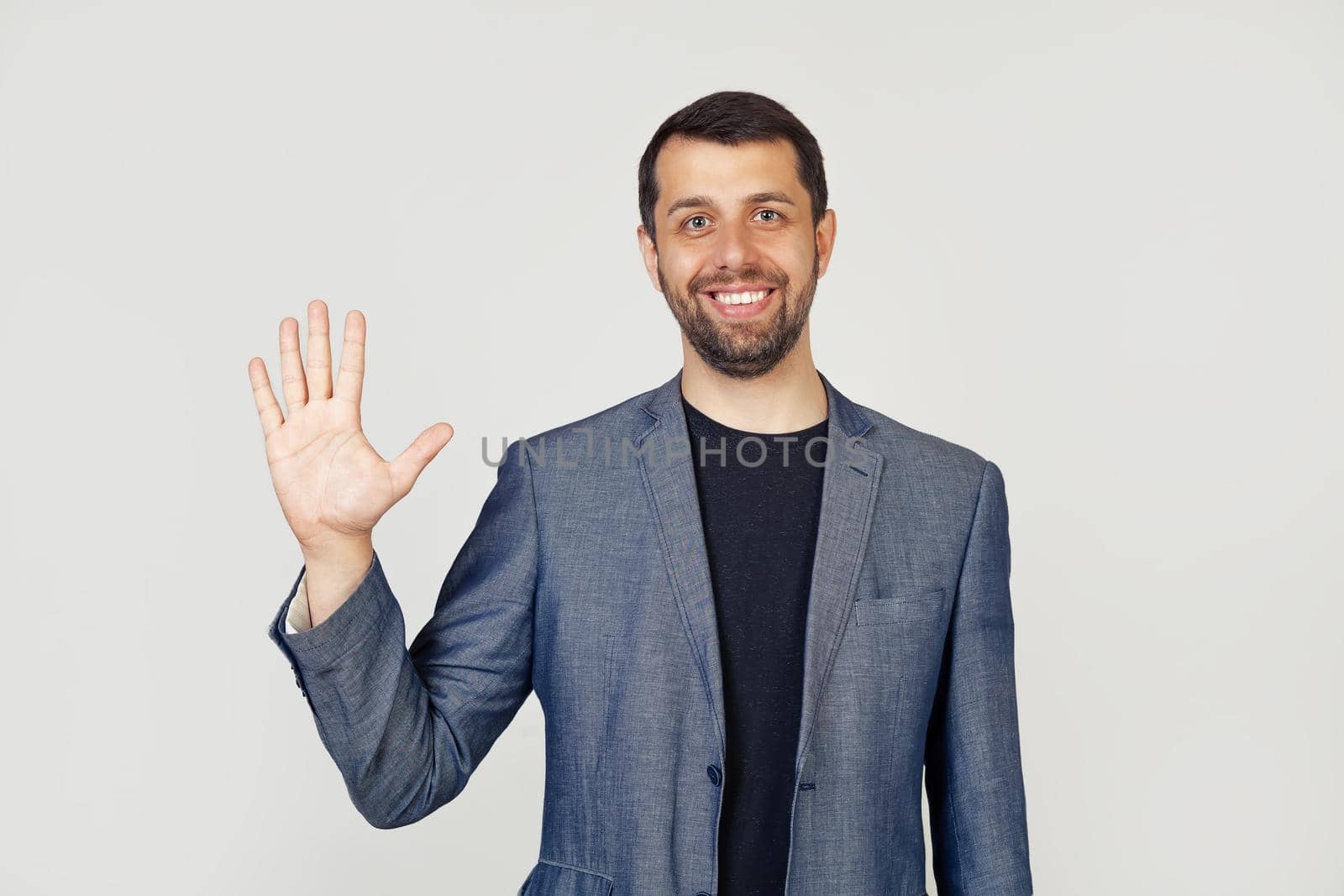 Young businessman man with beard smiling, showing number five with fingers on hand, smiling confidently and happily, looking into the camera. The man shows five fingers. Number 5.
