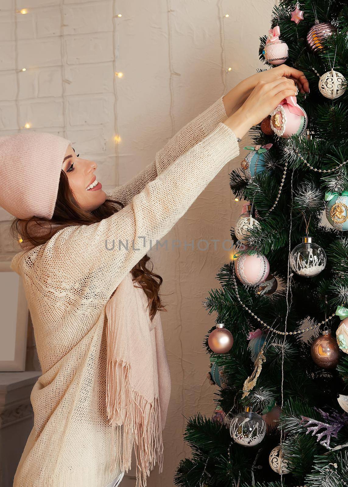 Happy young woman decorates the Christmas tree hang the ball on the tree. Christmas decoration, toys hanging on the tree, Christmas tree ball. New year and christmas holiday concept