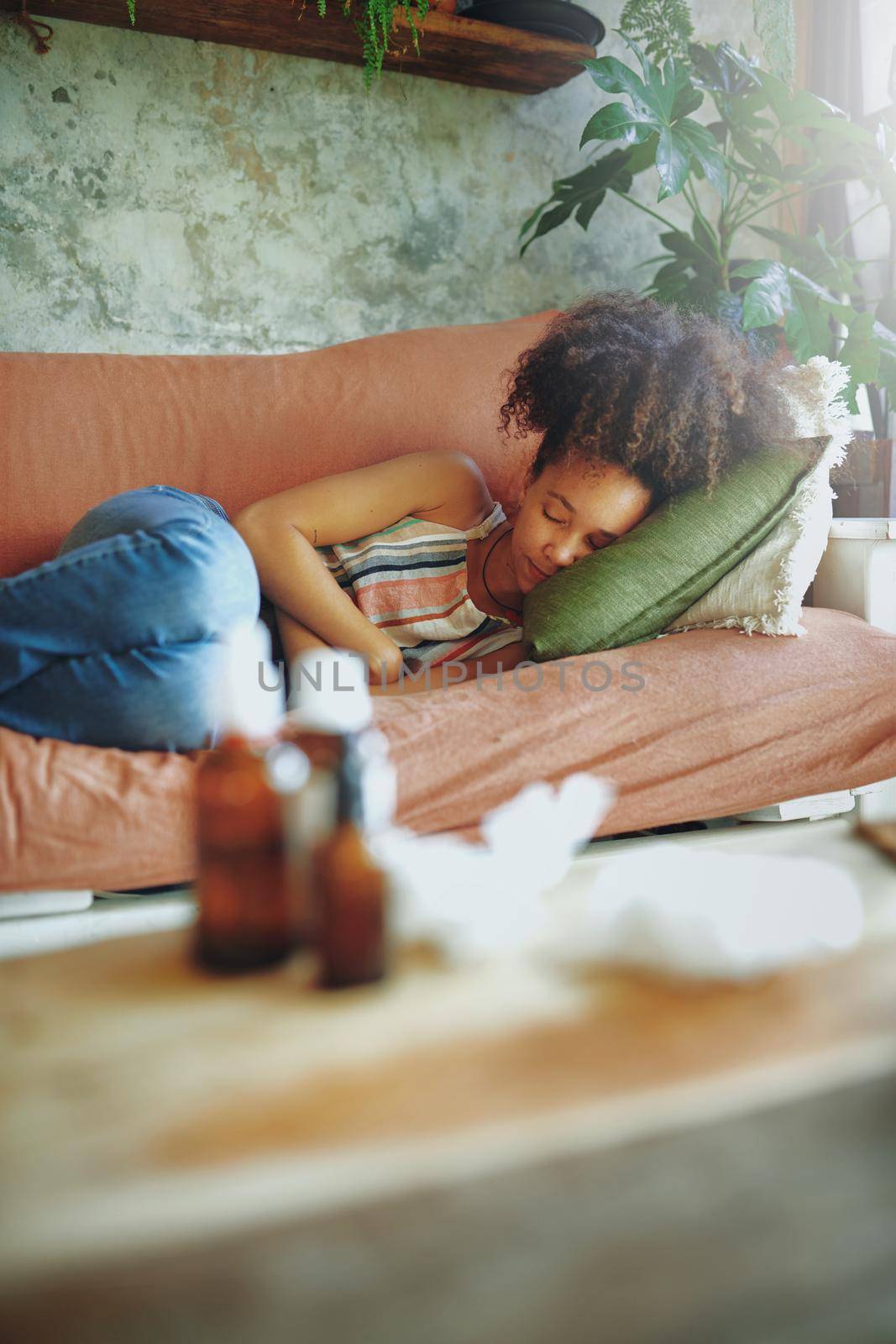 Shot of a young woman experiencing stomach pain while lying on the sofa at home stock photo