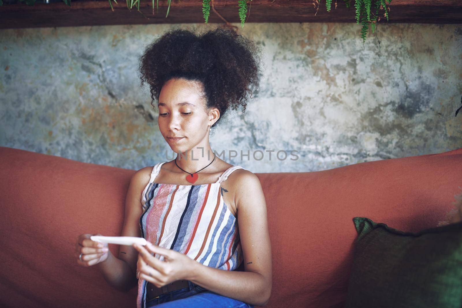 Shot of a young woman taking a pregnancy test on the sofa at home stock photo