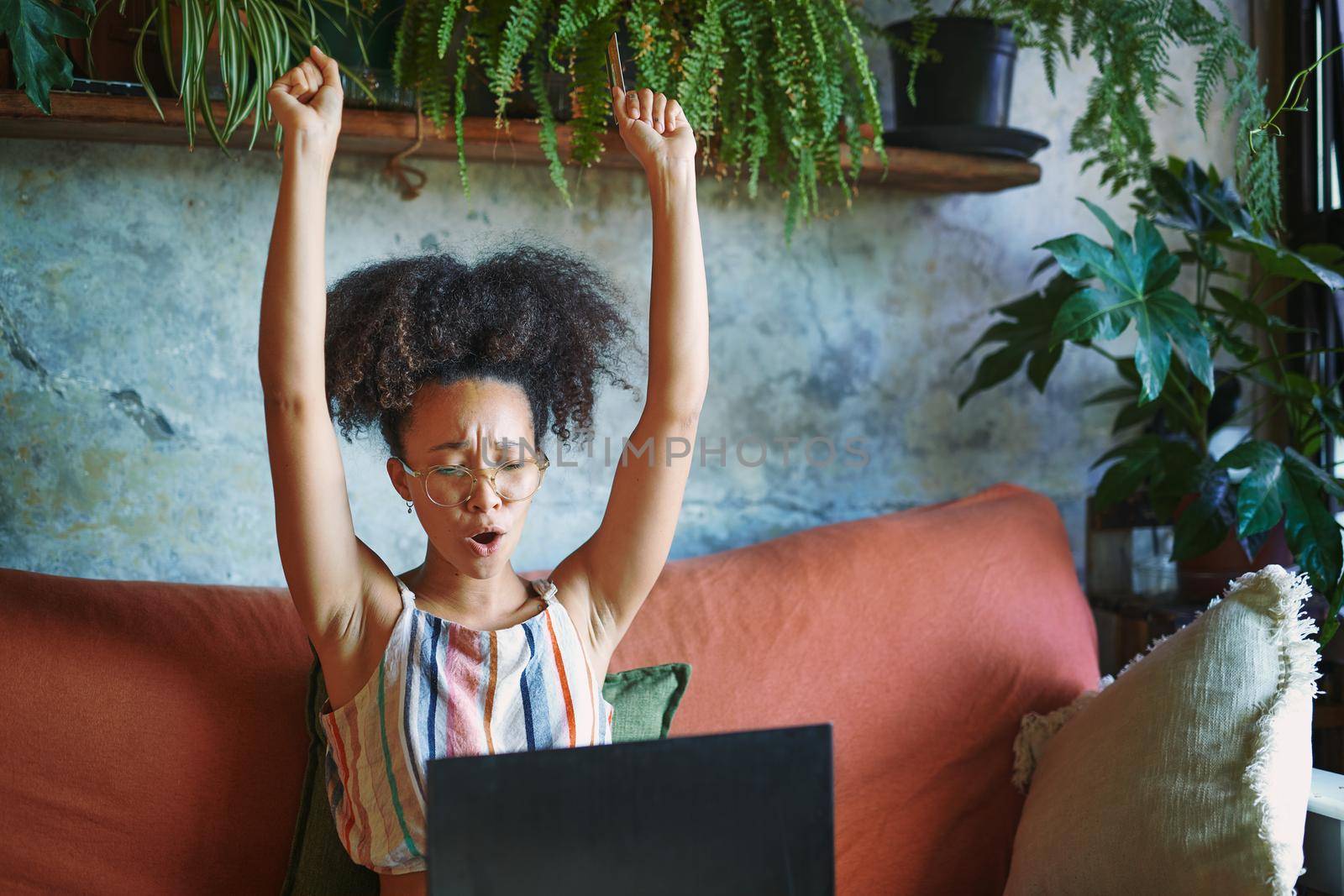 Shot of a beautiful African woman being cheerful on her couch