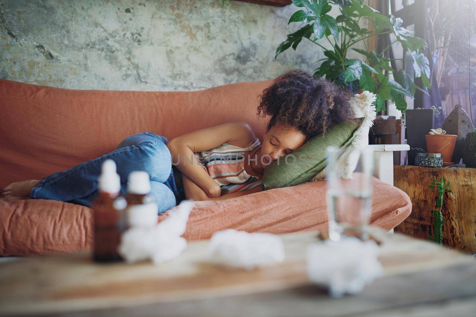 Shot of a young woman experiencing stomach pain while lying on the sofa at home stock photo