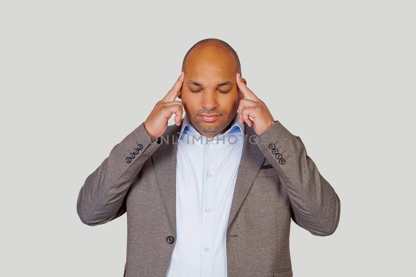 African American guy young man massaging whiskey with his fingers, trying to concentrate on work.