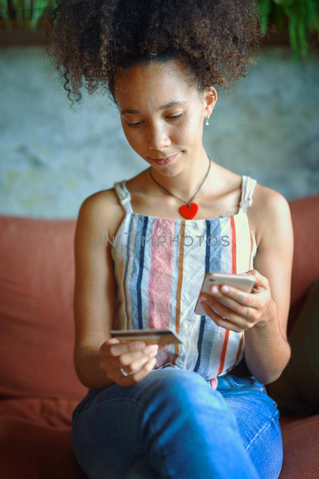Shot of a young woman using a cellphone while relaxing on a sofa at home