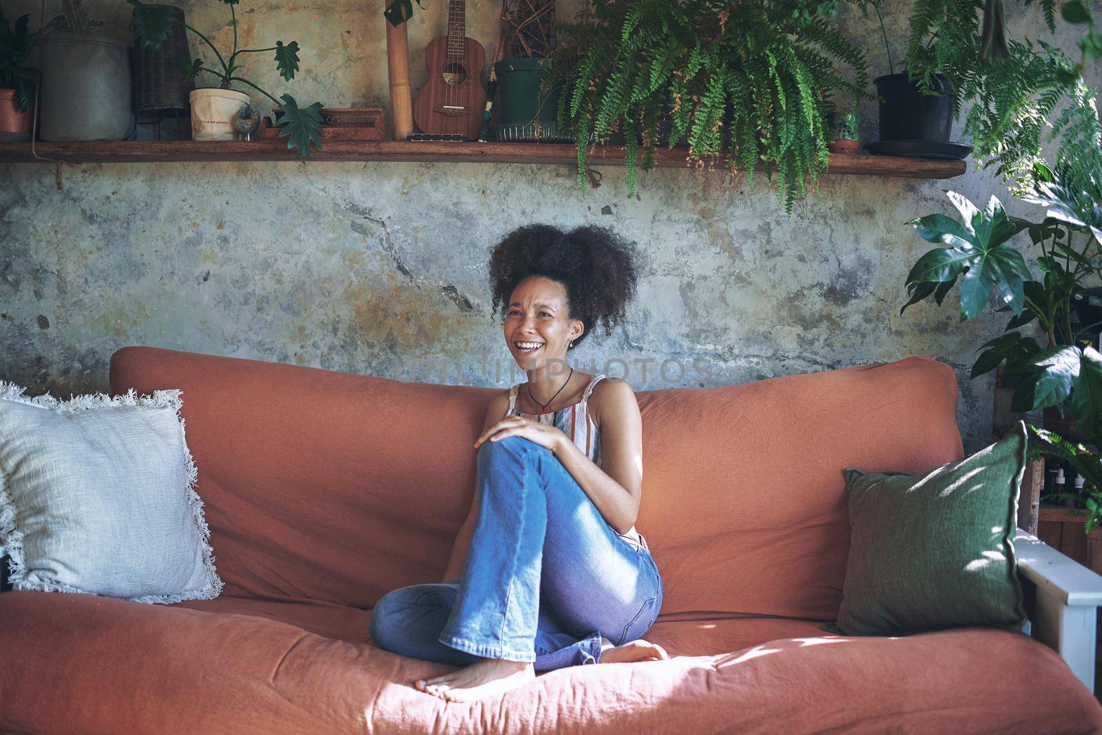 Shot of a beautiful African young woman relaxing on her sofa at home - Stock Photo