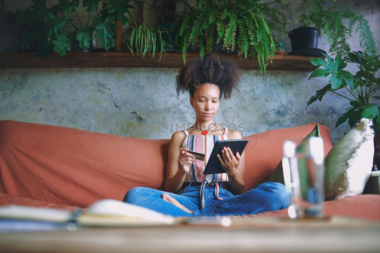 Shot of a beautiful African woman doing online shopping from her living room