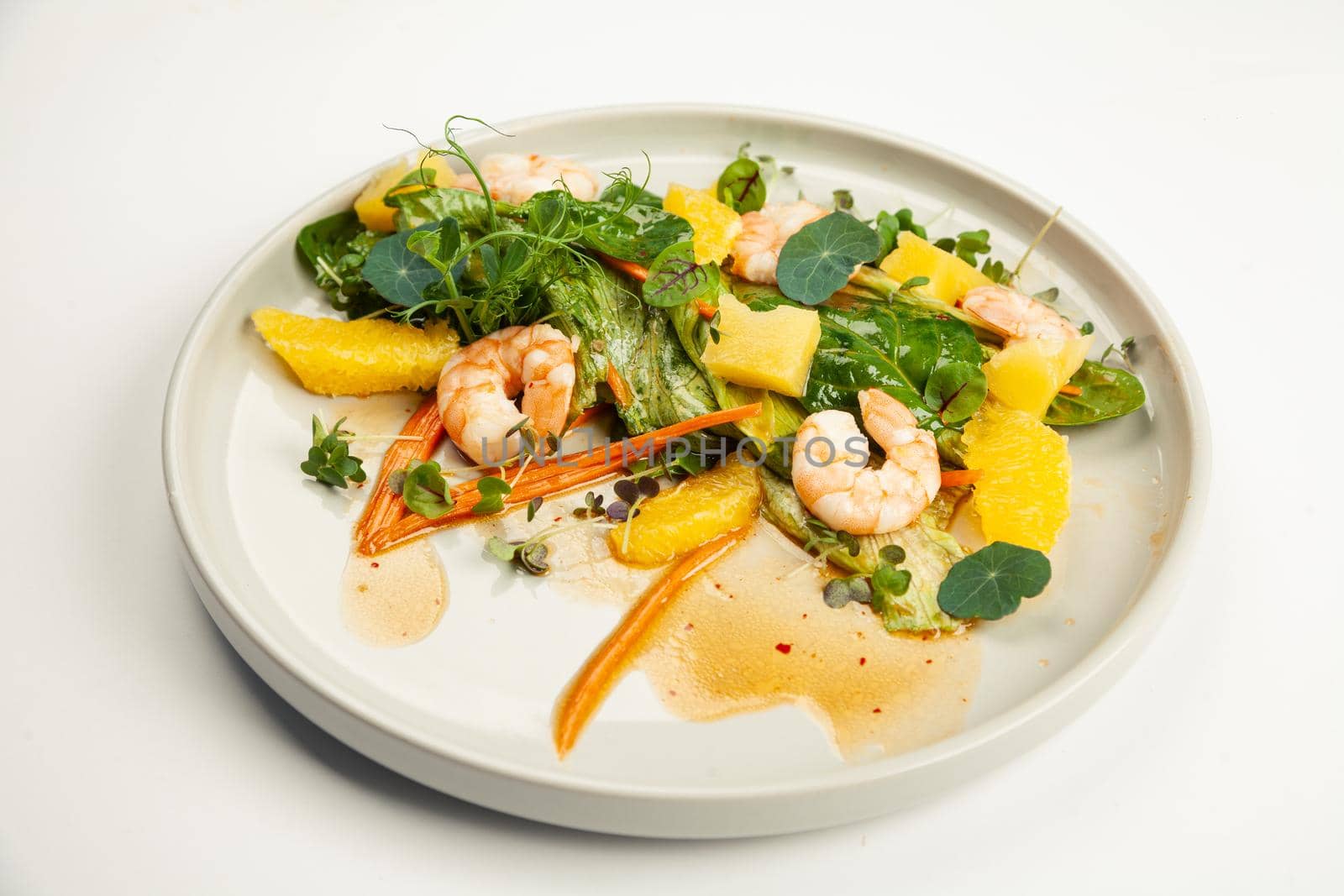 Shrimp salad in soy-ginger dressing on a plate. Ingredients Iceberg lettuce, shrimp, spinach, orange, pineapple, carrot, soy-ginger dressing. For restaurant menu.