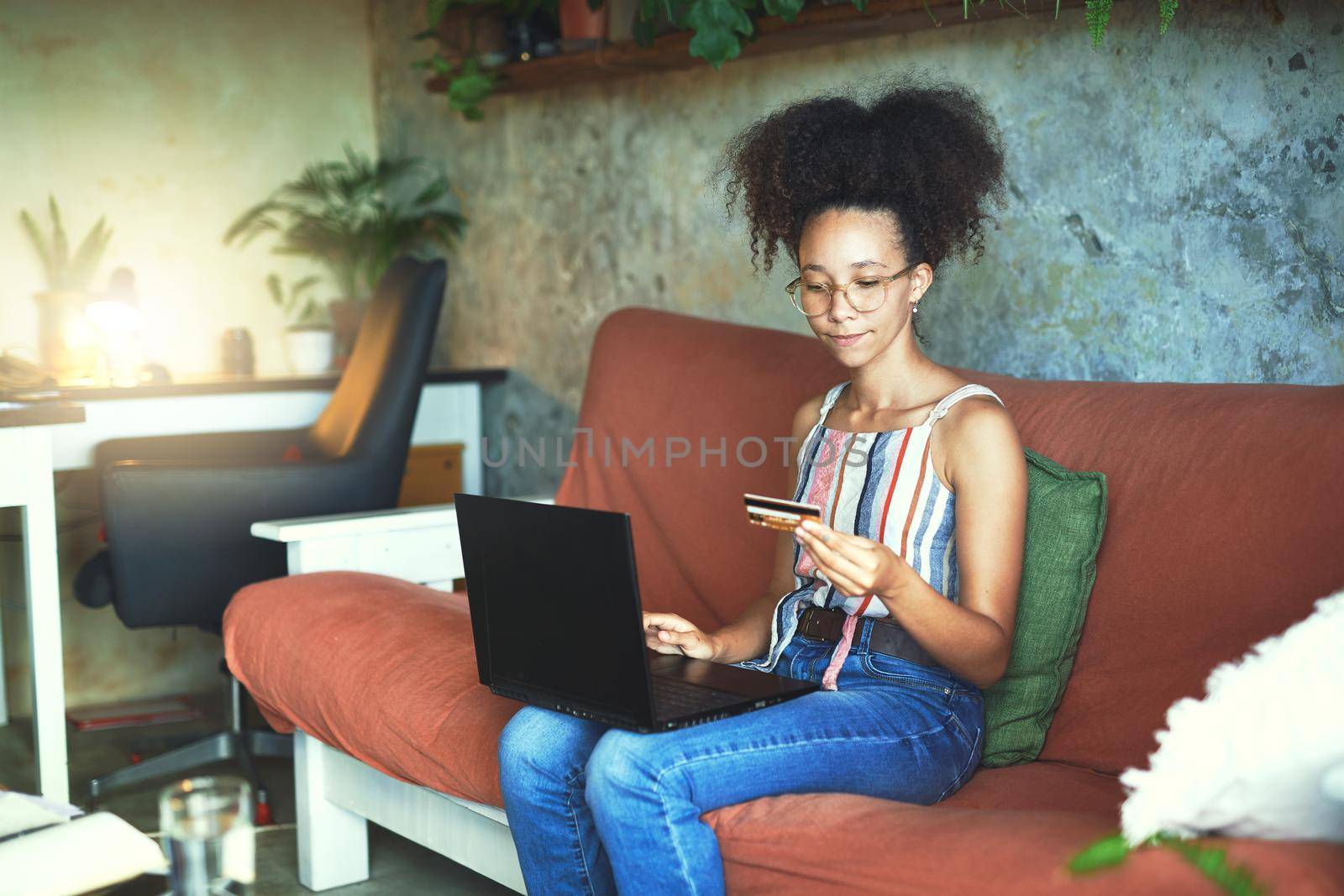 Shot of a beautiful African woman doing online banking from her Living room