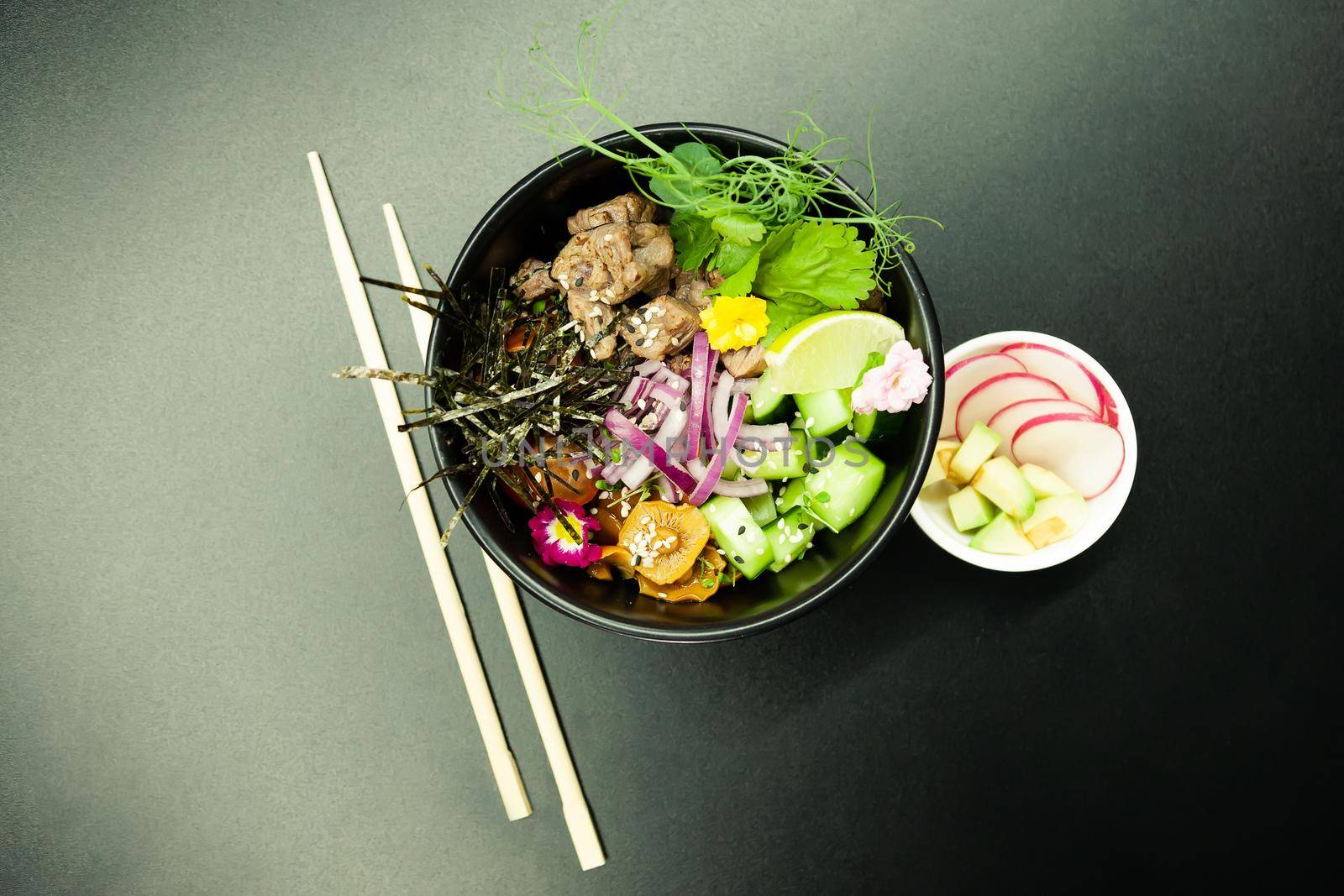 Poke salad with beef in a bowl. Ingredients Beef, Nameko mushrooms, cherry tomatoes, rice, cucumber, red onion, Kim Chi sauce, Ponzu sauce, nori, sesame seeds, cilantro, lime. Asian salad concept.