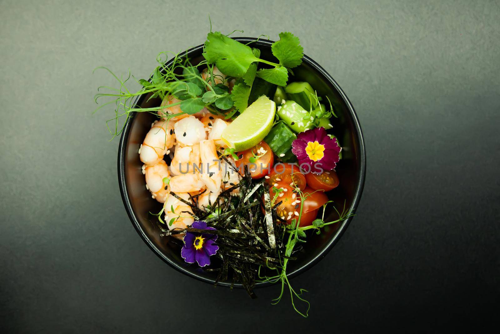 Poke salad with shrimp in a bowl. Ingredients Shrimp, blanched spinach, cherry tomatoes, rice, cucumber, soy-ginger sauce, Spicy sauce, nori, sesame, lime, cilantro. Asian seafood salad concept