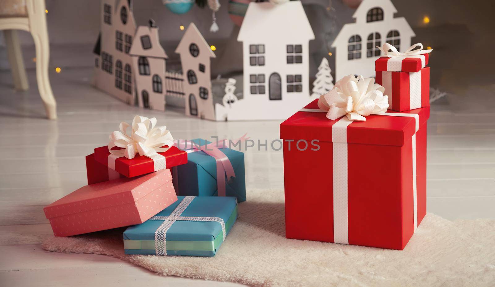 Beautiful Christmas gift boxes on the floor near the Christmas tree in the room. Holidays, gifts, new year and celebration concept - gift boxes on sheepskin. Stack of wrapped christmas gifts.