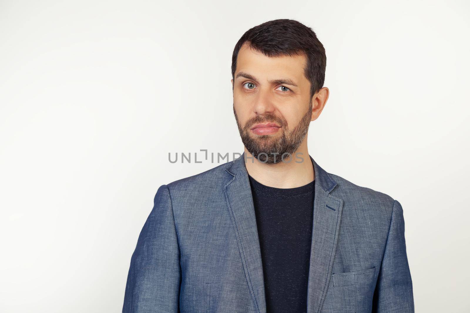 Young businessman man with a beard in a jacket, skeptical and nervous, frowning, upset because of the problem. Negative person. Portrait of a man on a gray background.