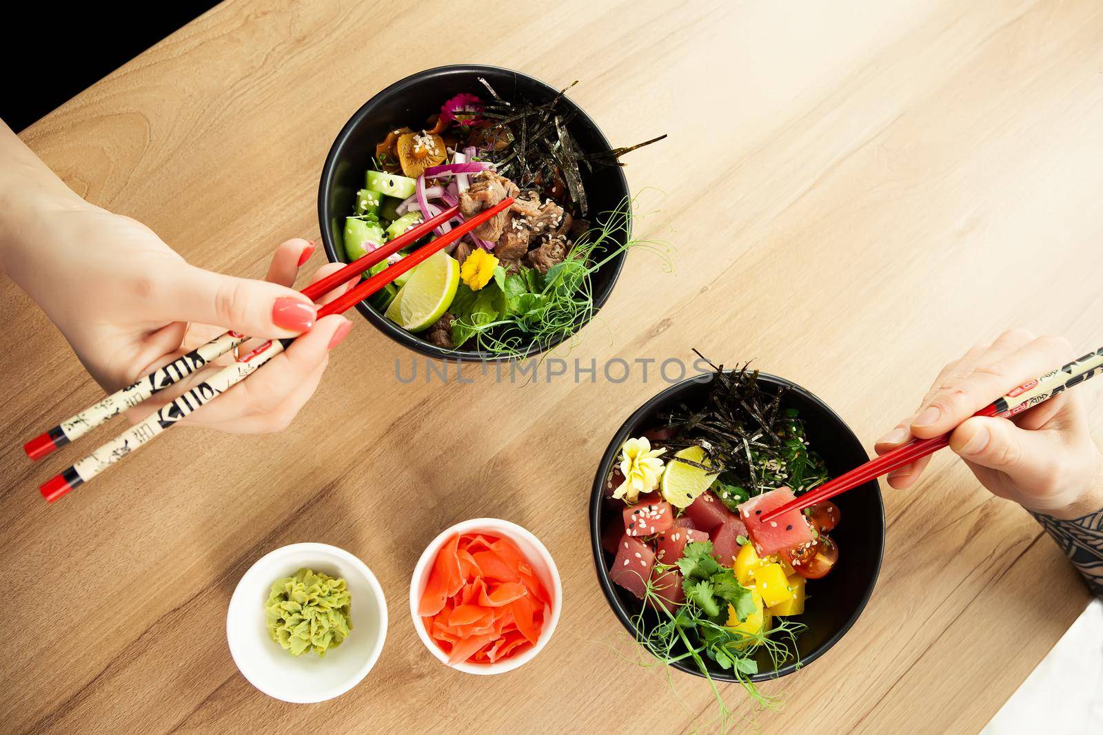 Man and woman eating poke salad with chopsticks. Dab tuna salad in a bowl. People in the restaurant eat salad with chopsticks. Asian seafood salad concept