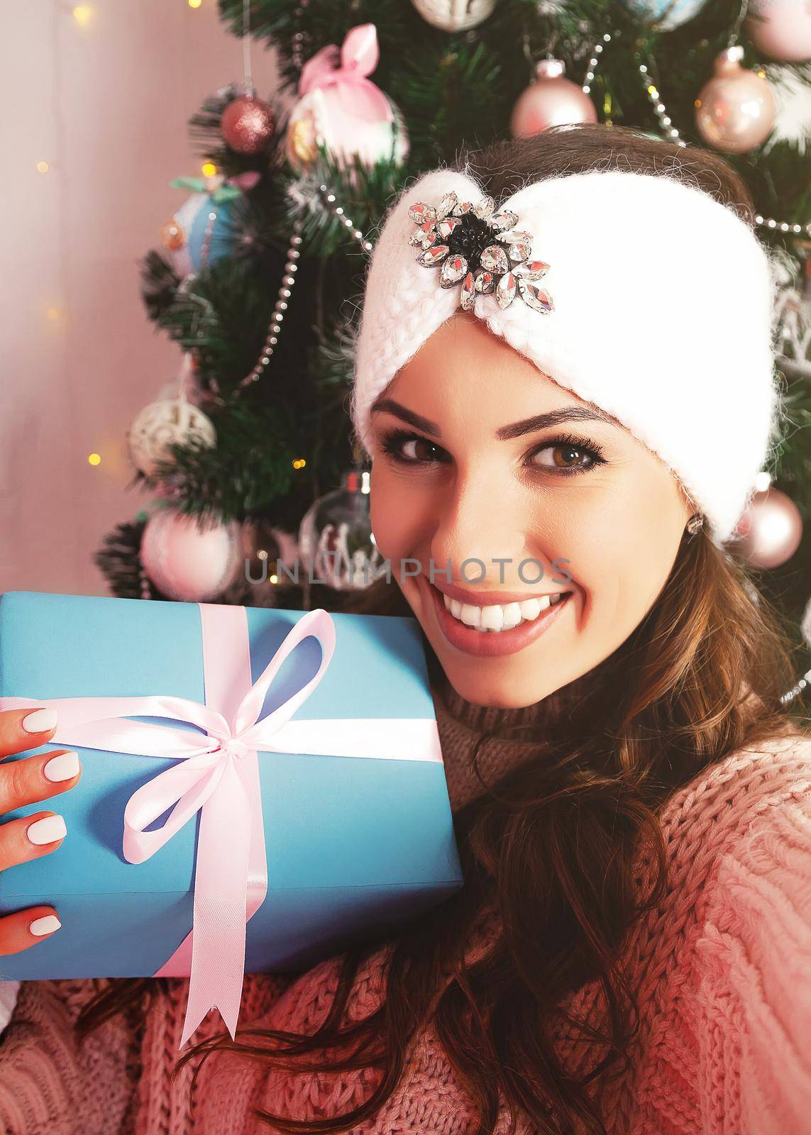 Self-portrait of a cheerful rejoicing girl removing a gift box with a Christmas tree behind her back. Young woman in winter clothes makes a photo with a gift for New Year and Christmas