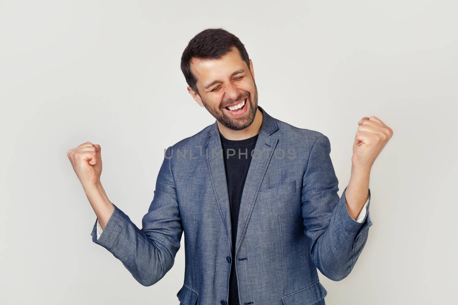 Portrait of an energetic young entrepreneur enjoying success. Young male businessman celebrates business success with hands up. Winner concept.