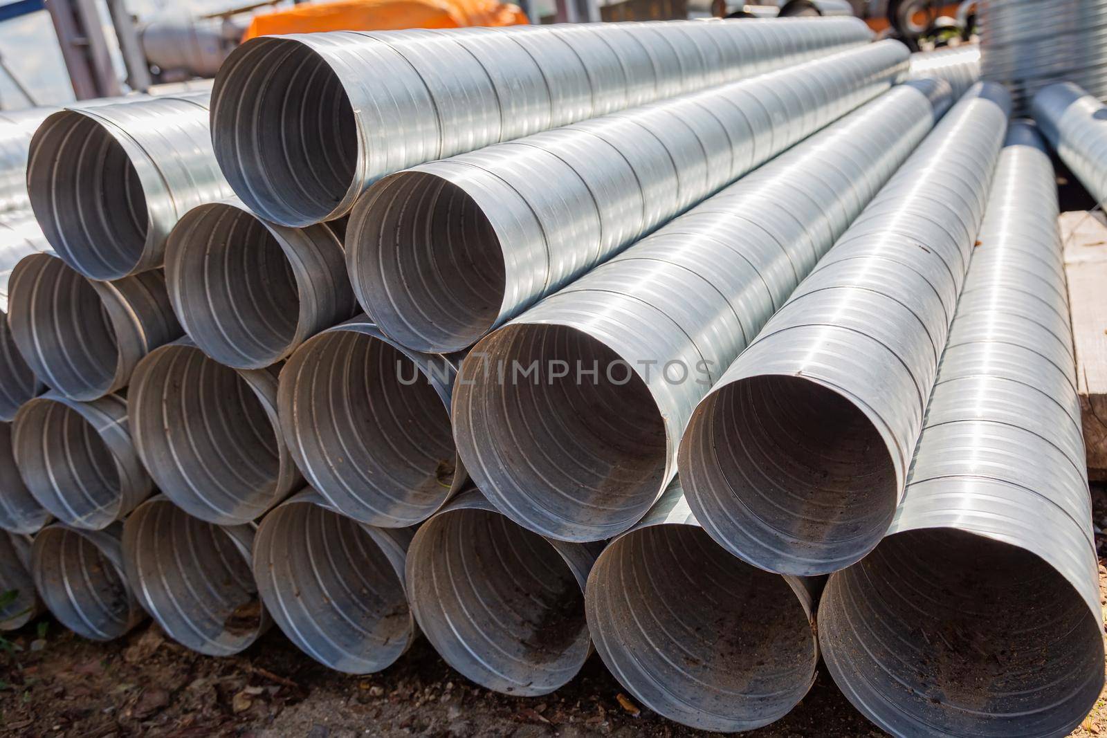 Ventilation pipes against the blue sky. Steel pipes, parts for the construction of air ducts for an industrial air conditioning system in a warehouse. Industrial ventilation equipment