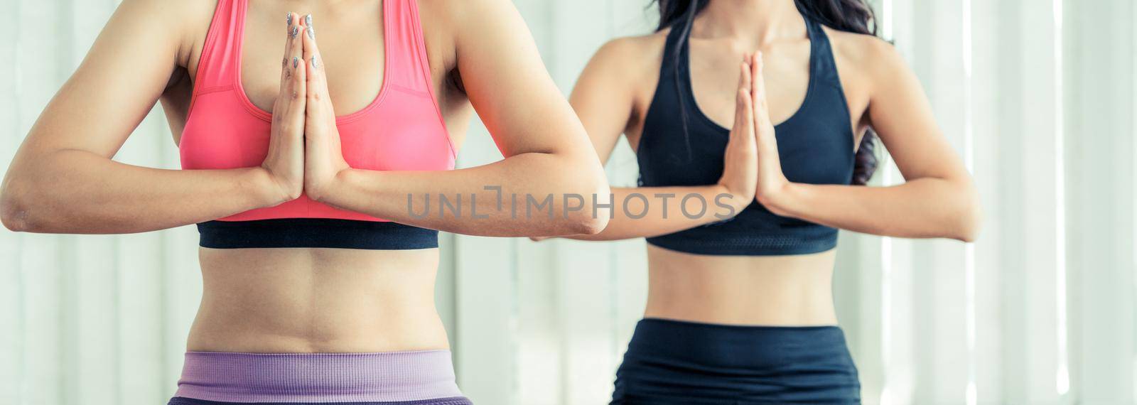 Women practicing yoga pose in fitness gym class by biancoblue