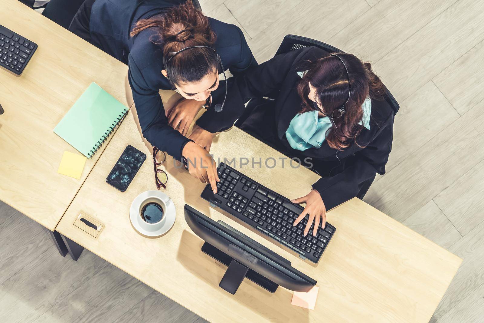 Business people wearing headset from top view in office working with computer to support remote customer or colleague. Call center, telemarketing agent service on telephone or video conference call.