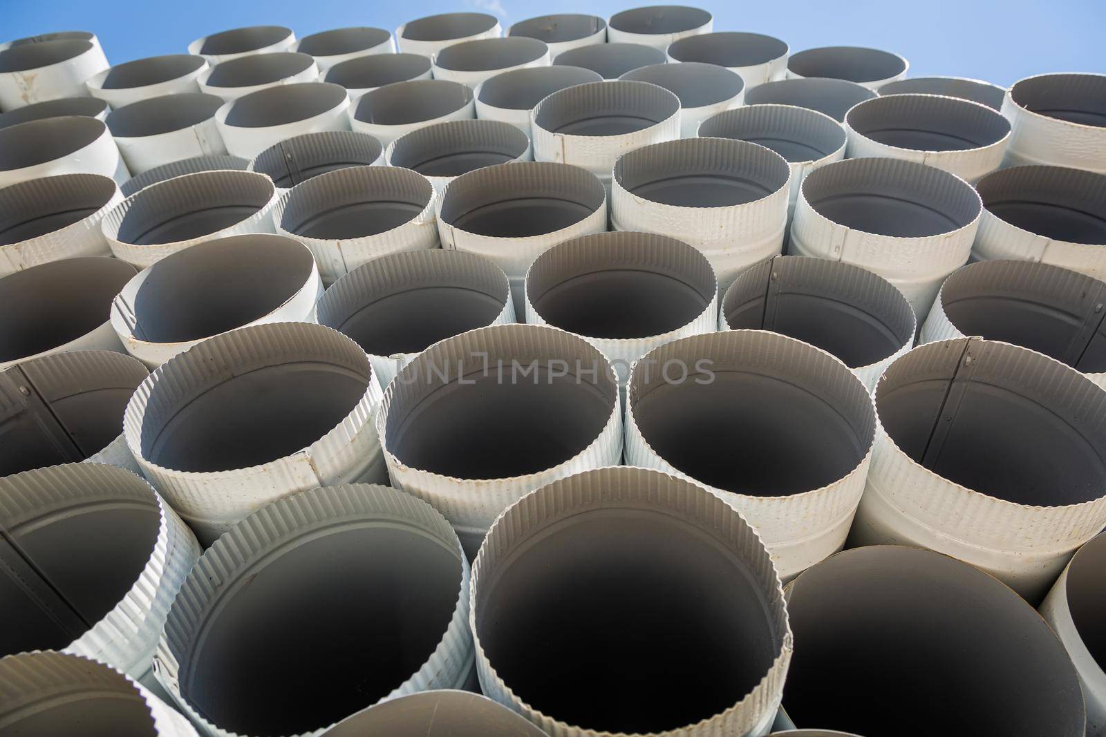 Downpipe warehouse. Steel pipes, parts for the construction of a roof drainage system in a warehouse. Stack of stainless steel pipes