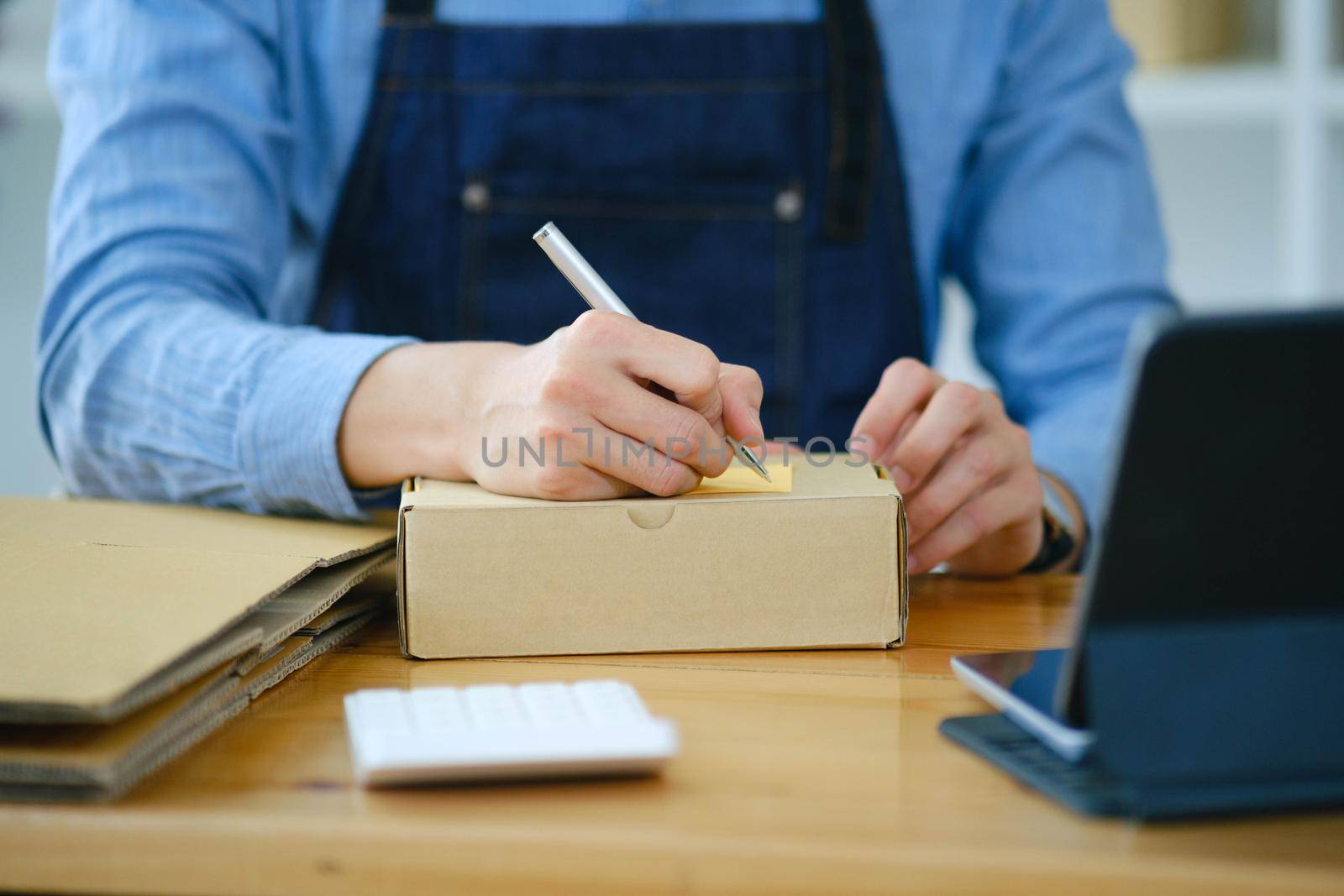 Young Asian businessman online store writing customer's address in shipping box..