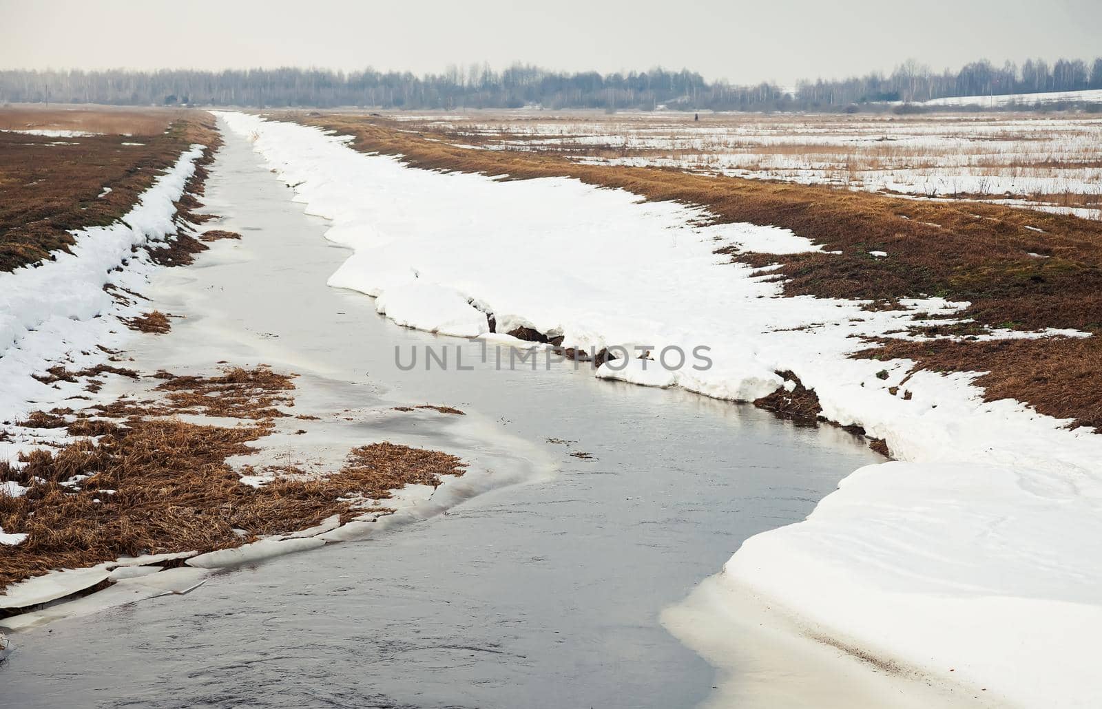 River in early spring on the bank of snow. The snow melts with the arrival of heat near the banks of the river. In the spring, the ice comes down the rivers, melting ice comes down