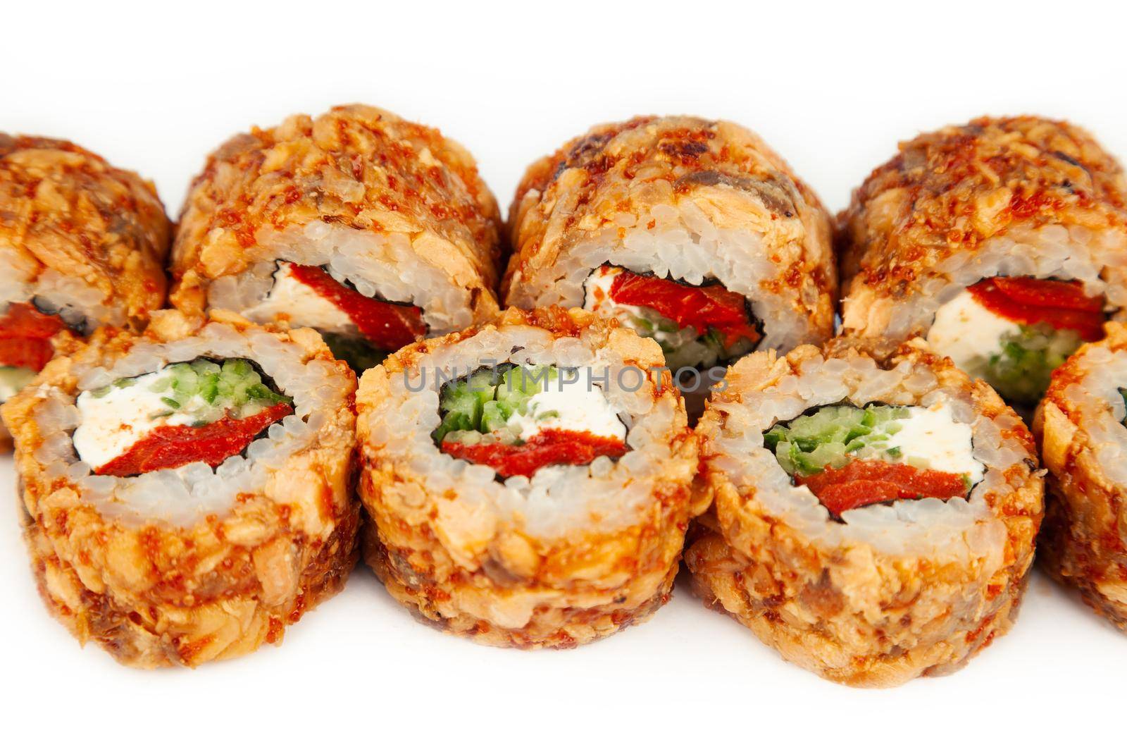 Sushi Roll with fried salmon in Teriyaki sauce on a white plate, ingredients Fried salmon, cream cheese, cucumber, baked pepper, flying fish roe, Spicy sauce, rice, nori. For the restaurant menu