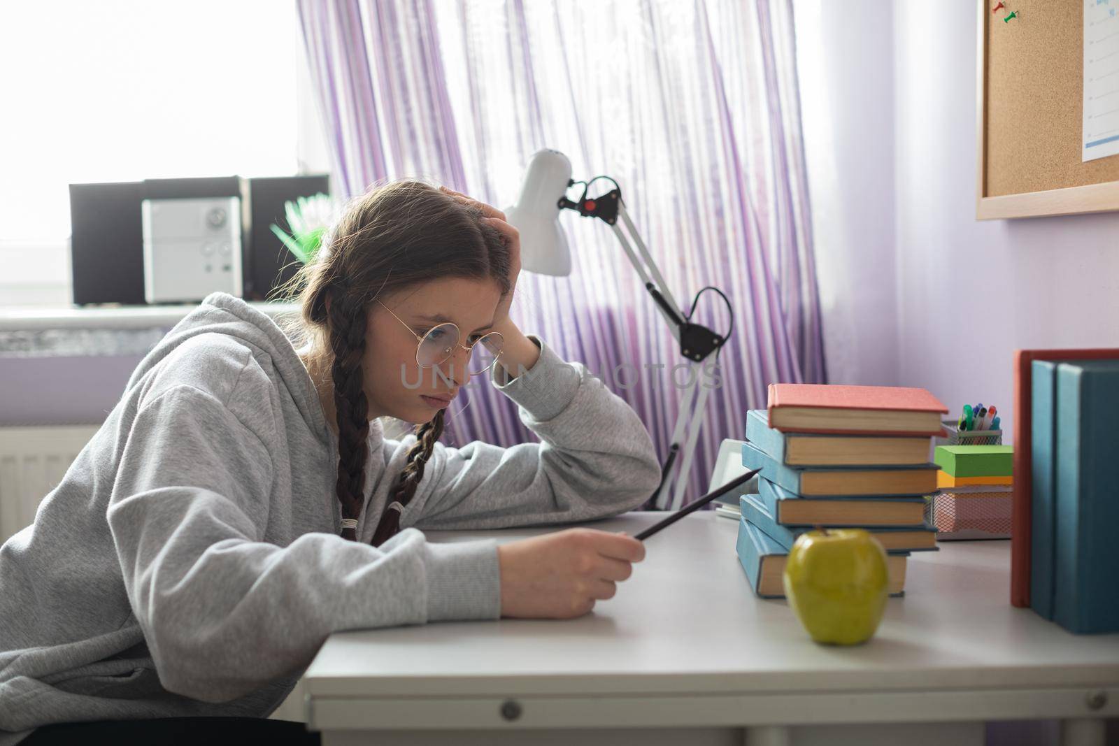 A girl sits at her desk and wonders how she will read all those school readings during the school year. A young girl with pigtails.