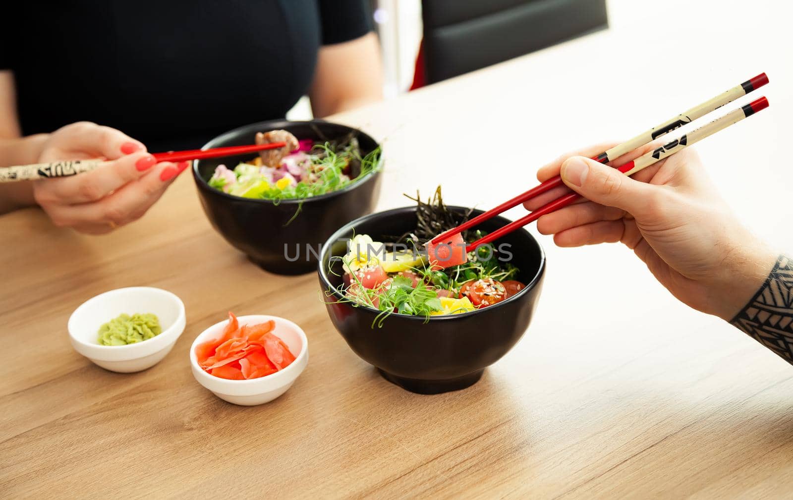 A man adds soy sauce to Poke salad. Guy young man dressing salad with sauce in a restaurant or cafe
