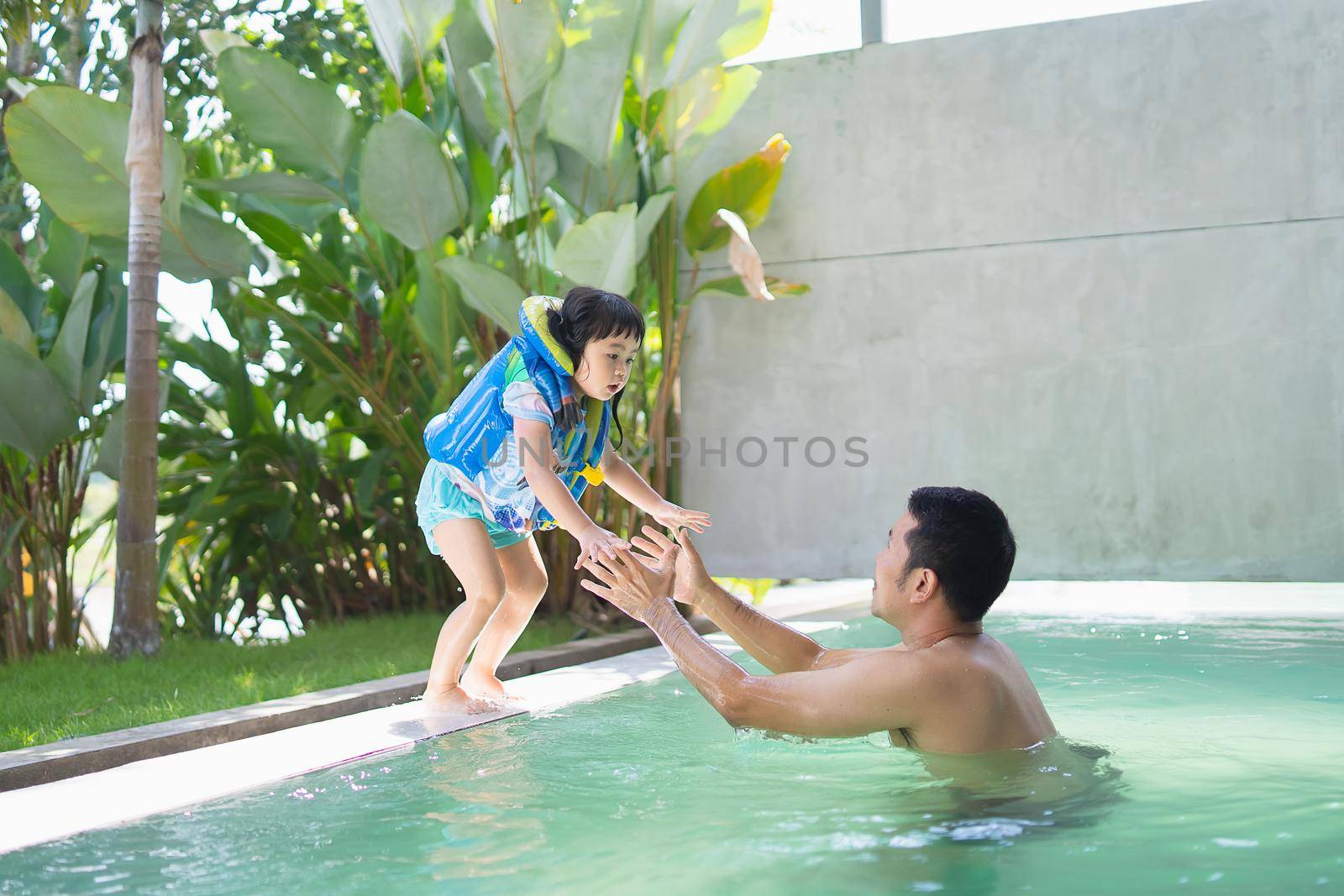 Father and daughter swimming playing in the pool, smiling and laughing. Having fun in the pool at the resort hotel, family happy concept.