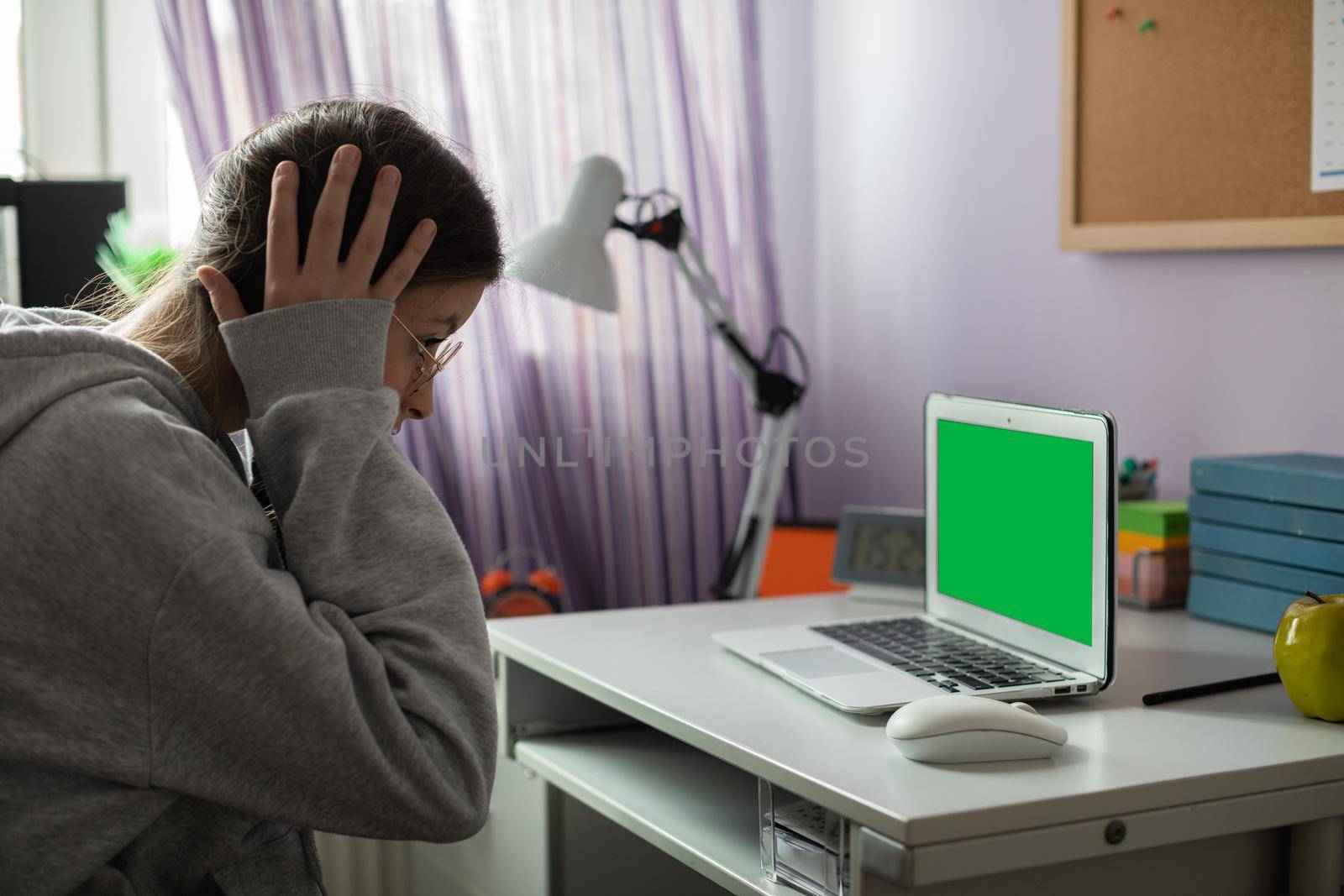 Green screen on laptop. A school girl found unbelievable news about her peers on the internet. A young girl with pigtails.