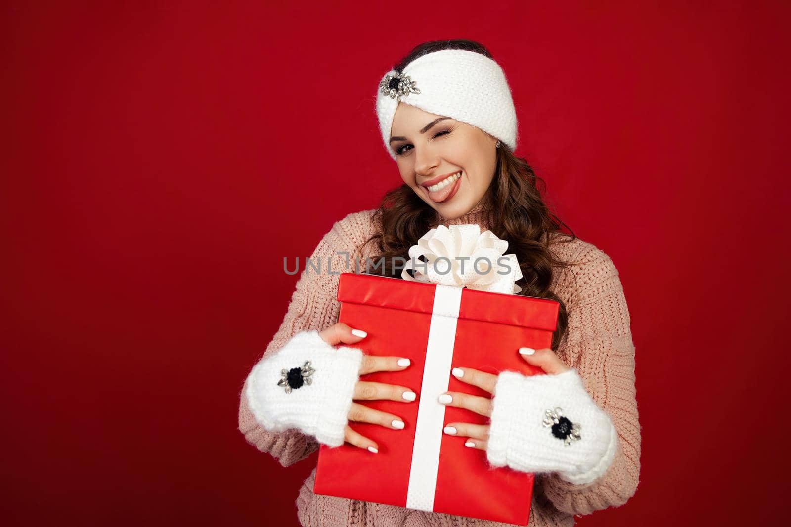 Happy woman holding a gift box. Portrait of happy smiling girl looking at delivered wrapped box isolated on red background