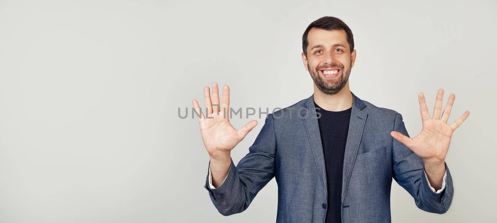 Young businessman man with beard smiling, showing number ten with fingers on his hand, smiling confidently and happily, looking at the camera.