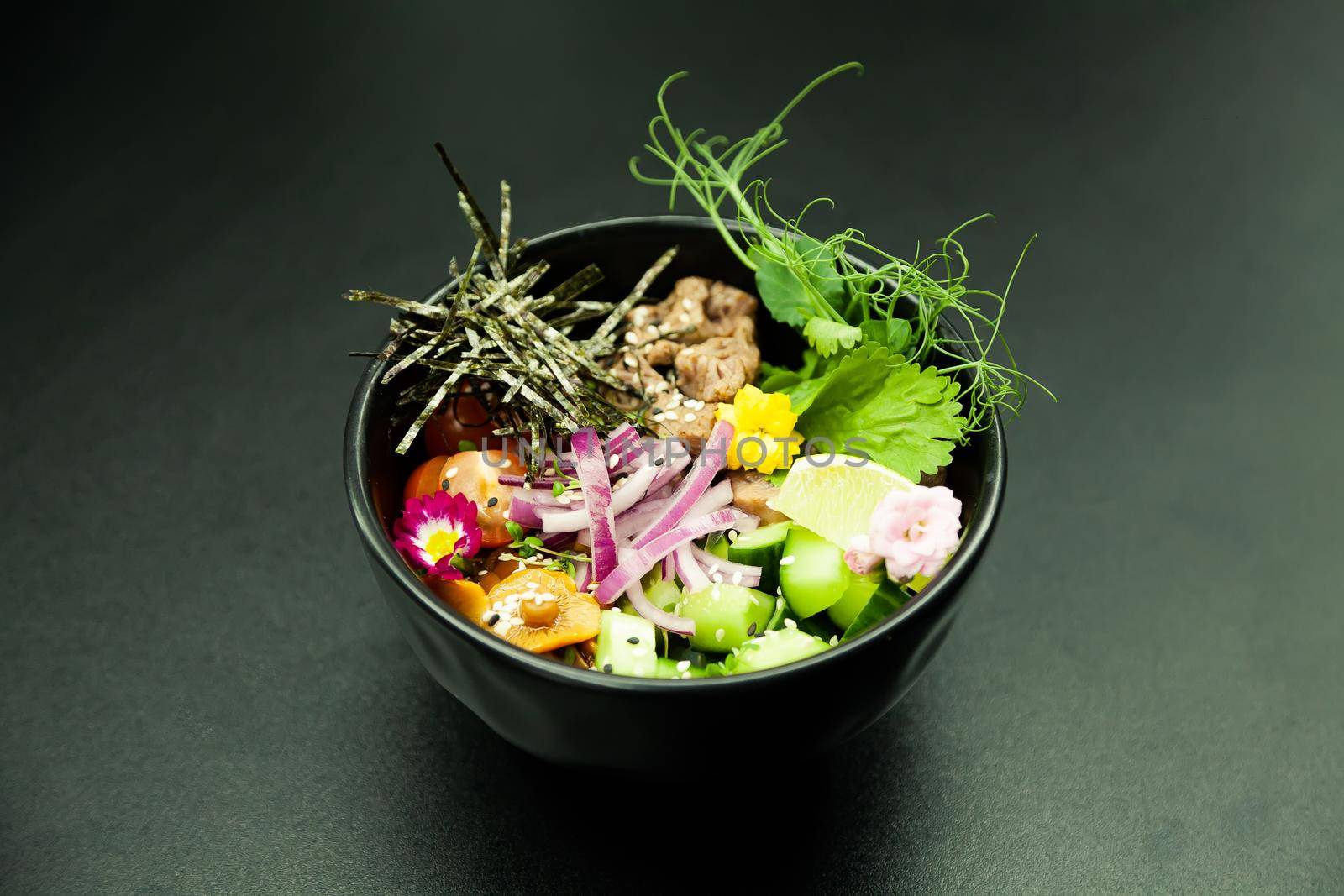 Poke salad with beef in a bowl. Ingredients Beef, Nameko mushrooms, cherry tomatoes, rice, cucumber, red onion, Kim Chi sauce, Ponzu sauce, nori, sesame seeds, cilantro, lime. Asian salad concept.