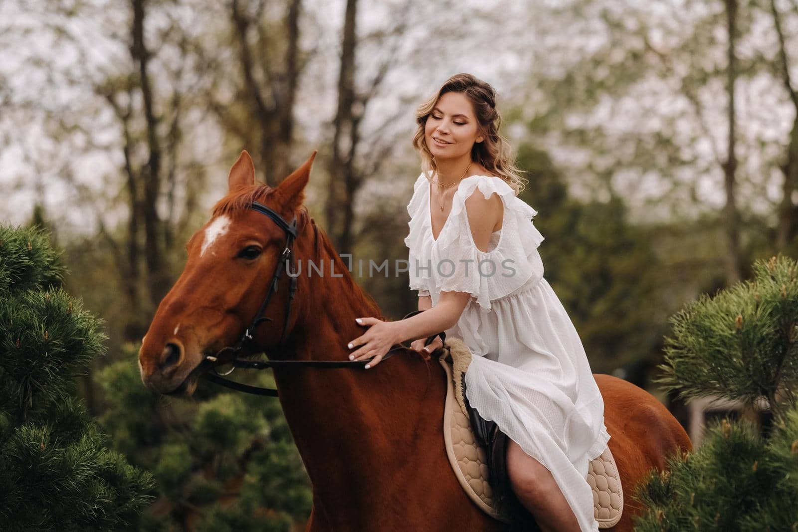 A woman in a white sundress riding a horse near a farm.