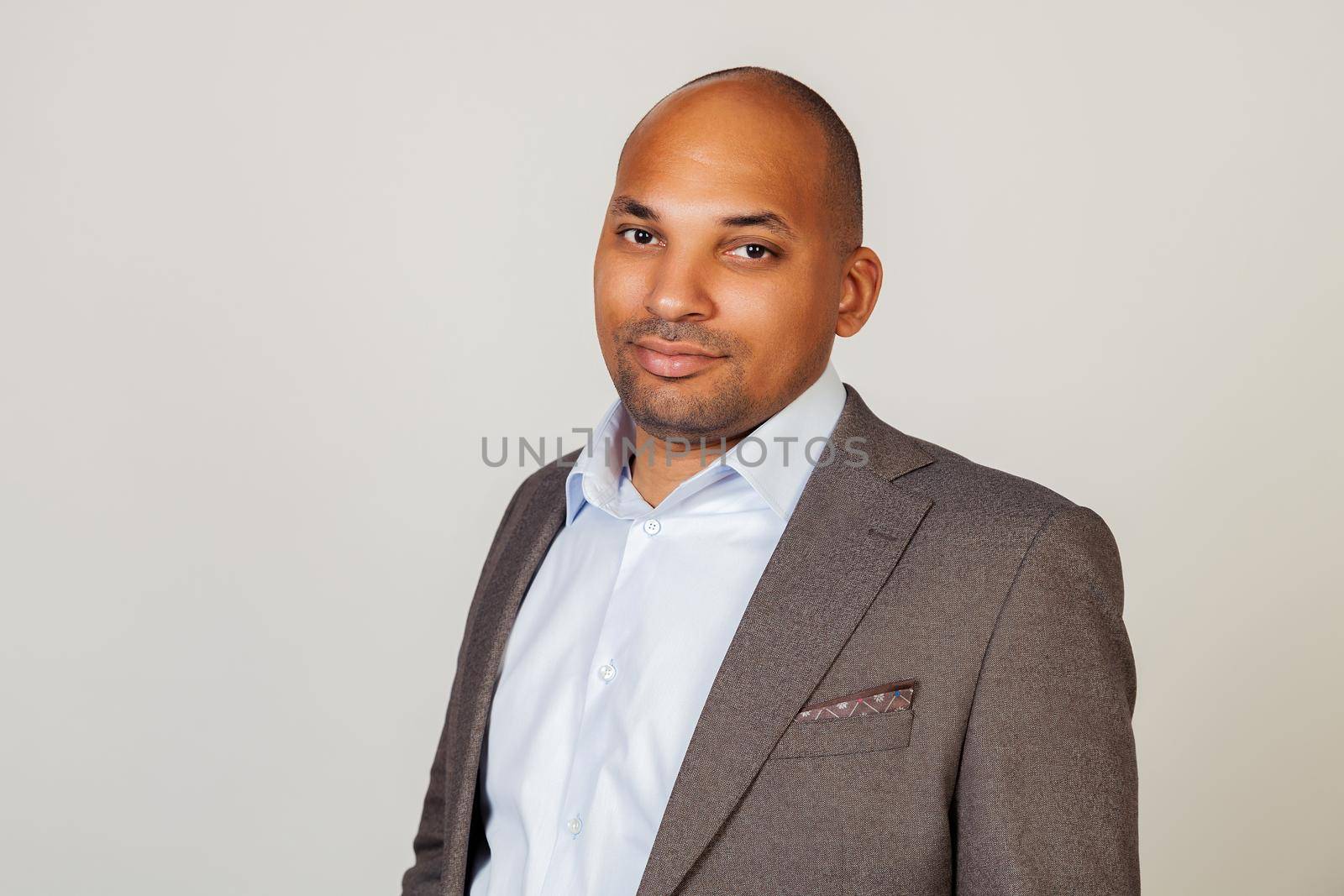 African American man looking into the camera with a serious expression. Business man businessman in classic suit looking at camera while standing on gray background