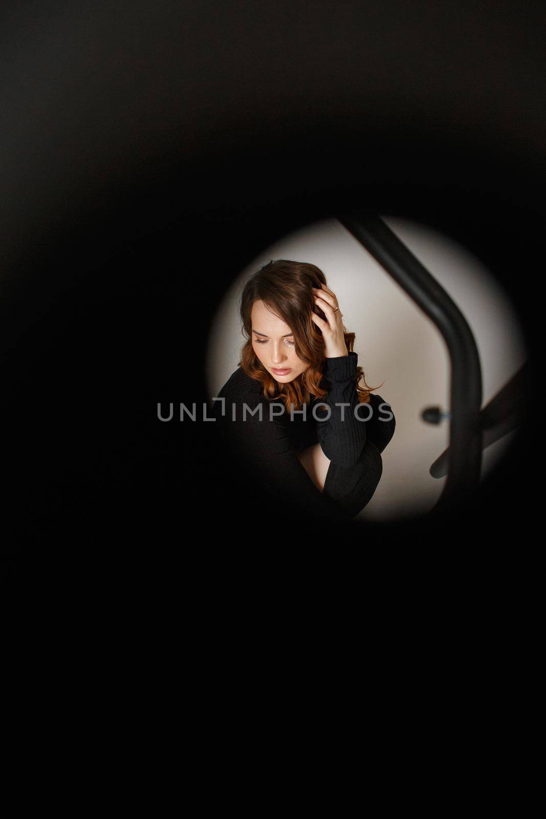 A girl in a black skirt photographed through a black chair.
