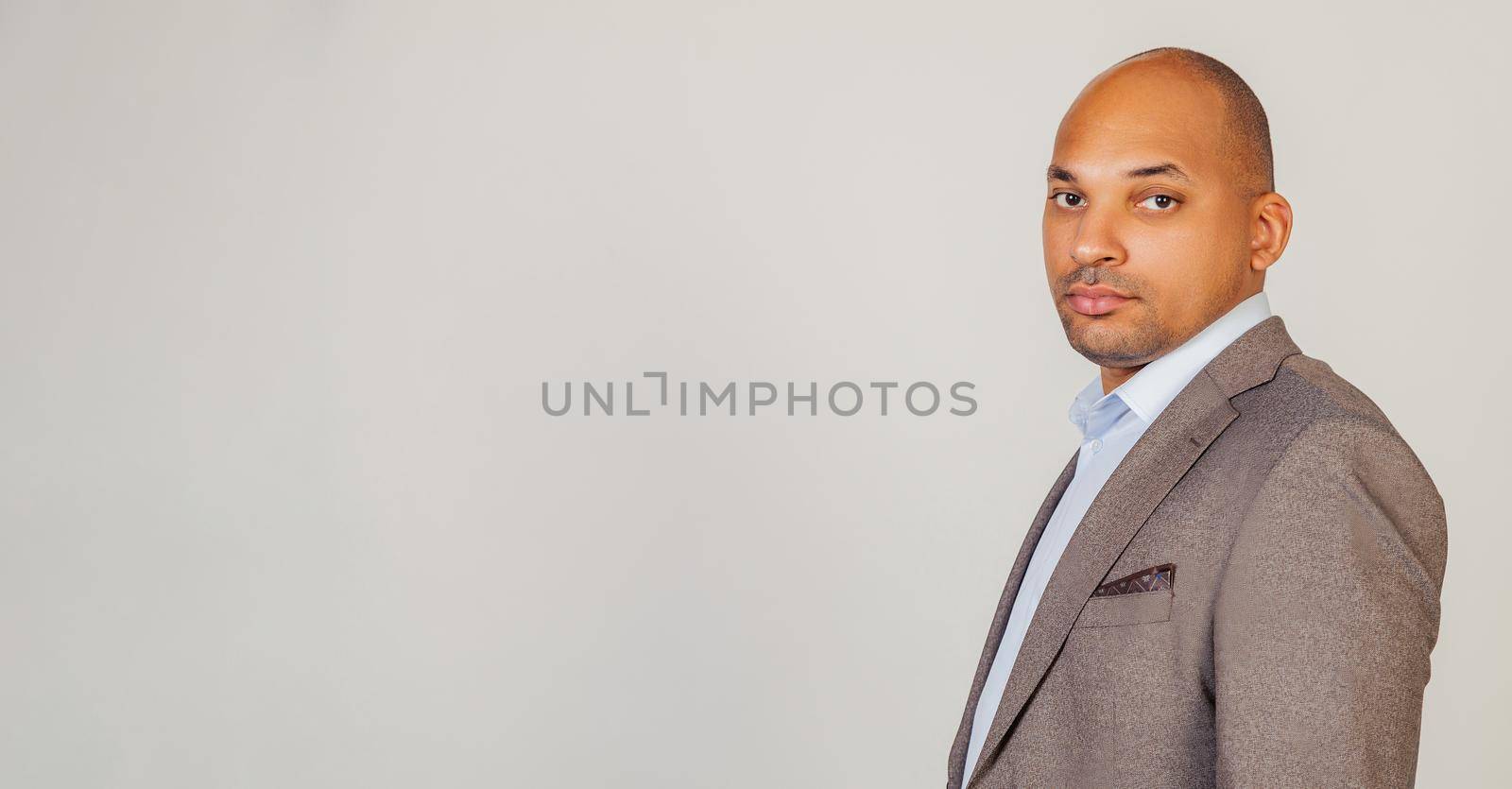 African American man looking into the camera with a serious expression. Business man businessman in classic suit looking at camera while standing on gray background