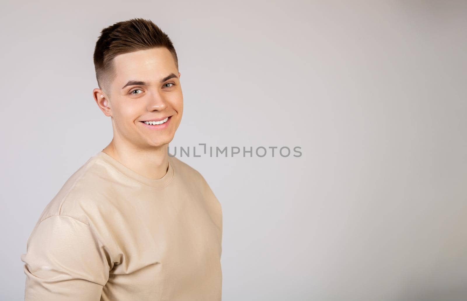 Handsome young man with stylish hairstyle looking at the camera with a smile on his face. Photo of young attractive handsome modern freelancer, entrepreneur, student looking at camera.