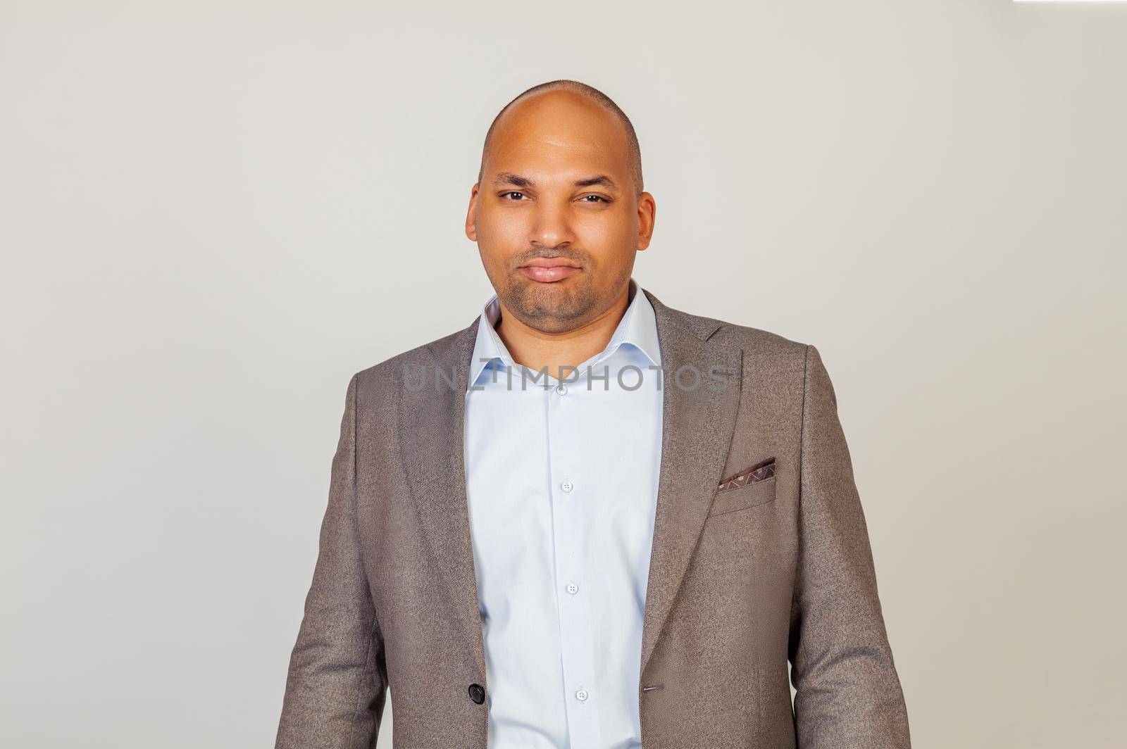 African American man looking into the camera with a serious expression. Business man businessman in classic suit looking at camera while standing on gray background
