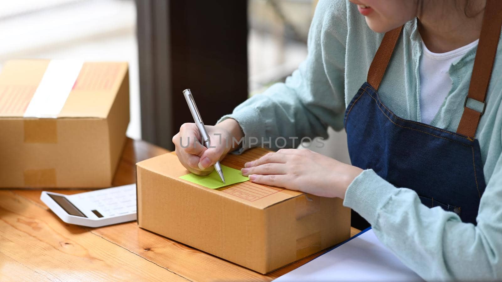 Start up business entrepreneur writing address on cardboard box. Online selling, E-commerce concept.