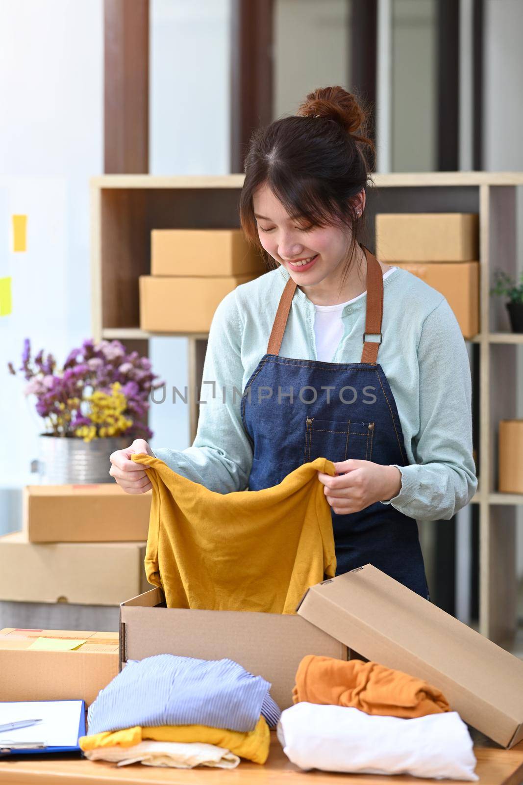 Happy small business owner packing product in cardboard box for delivery to customers. Online selling, E-commerce concept.